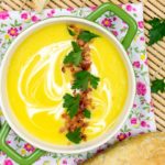 Tigela de sopa creme de mandioquinha com bacon crocante e salsinha picada por cima.