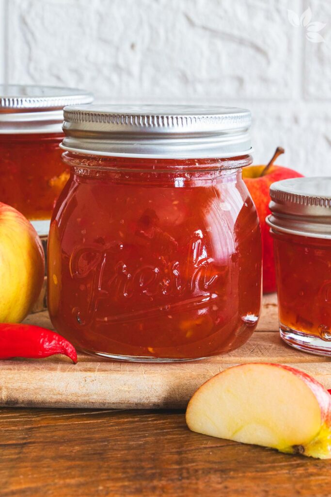 geleia de pimenta caseira com maçãs e pimentas vermelhas sobre tábua de madeira