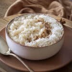 Close no arroz doce com coco e canela, mostrando a cremosidade da receita afetiva.